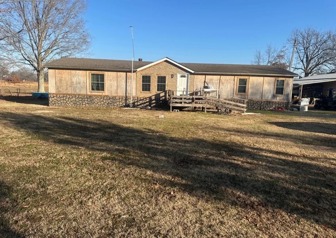 Manufactured home before exterior painting, with worn, faded tan and brown board-and-batten siding