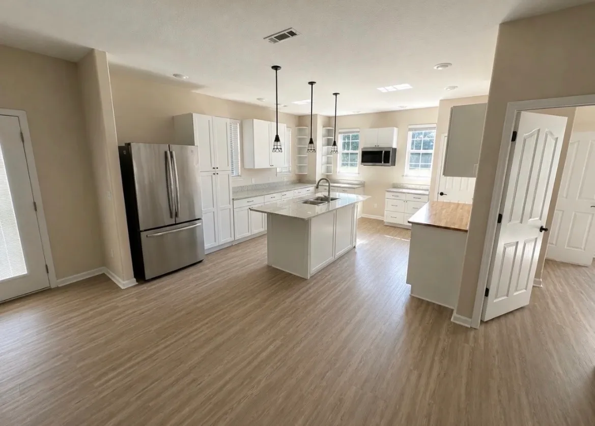 The same open-concept space after its refresh, cleaned and staged, with light, warm wood-look plank flooring and soft neutral walls