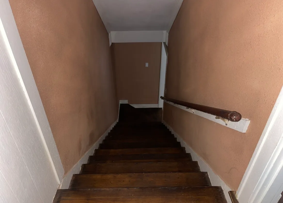 The same stairwell after interior painting, with the paneling covered in a warm, smooth neutral tan finish