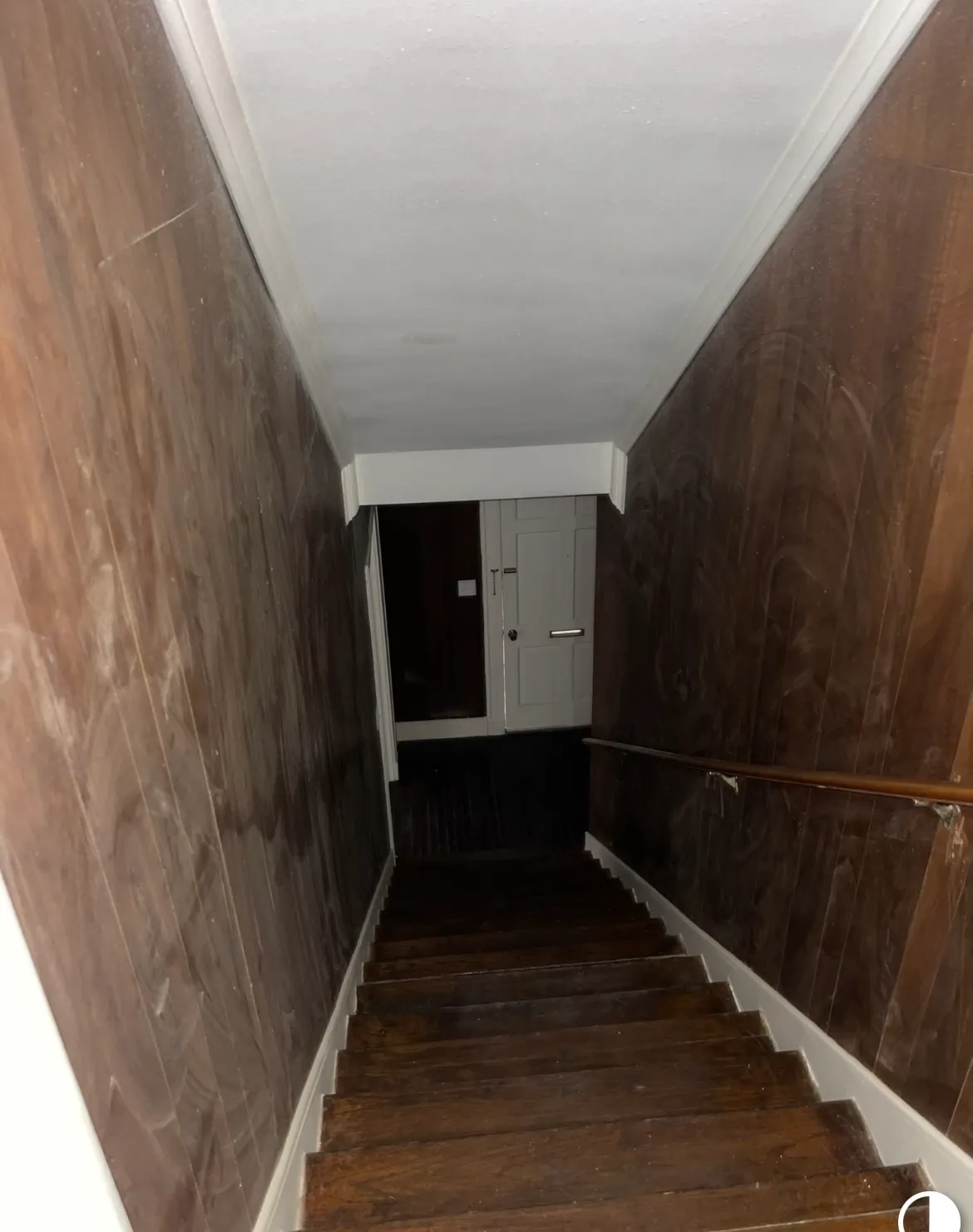Stairwell before interior painting, with dark, dated wood-panel walls