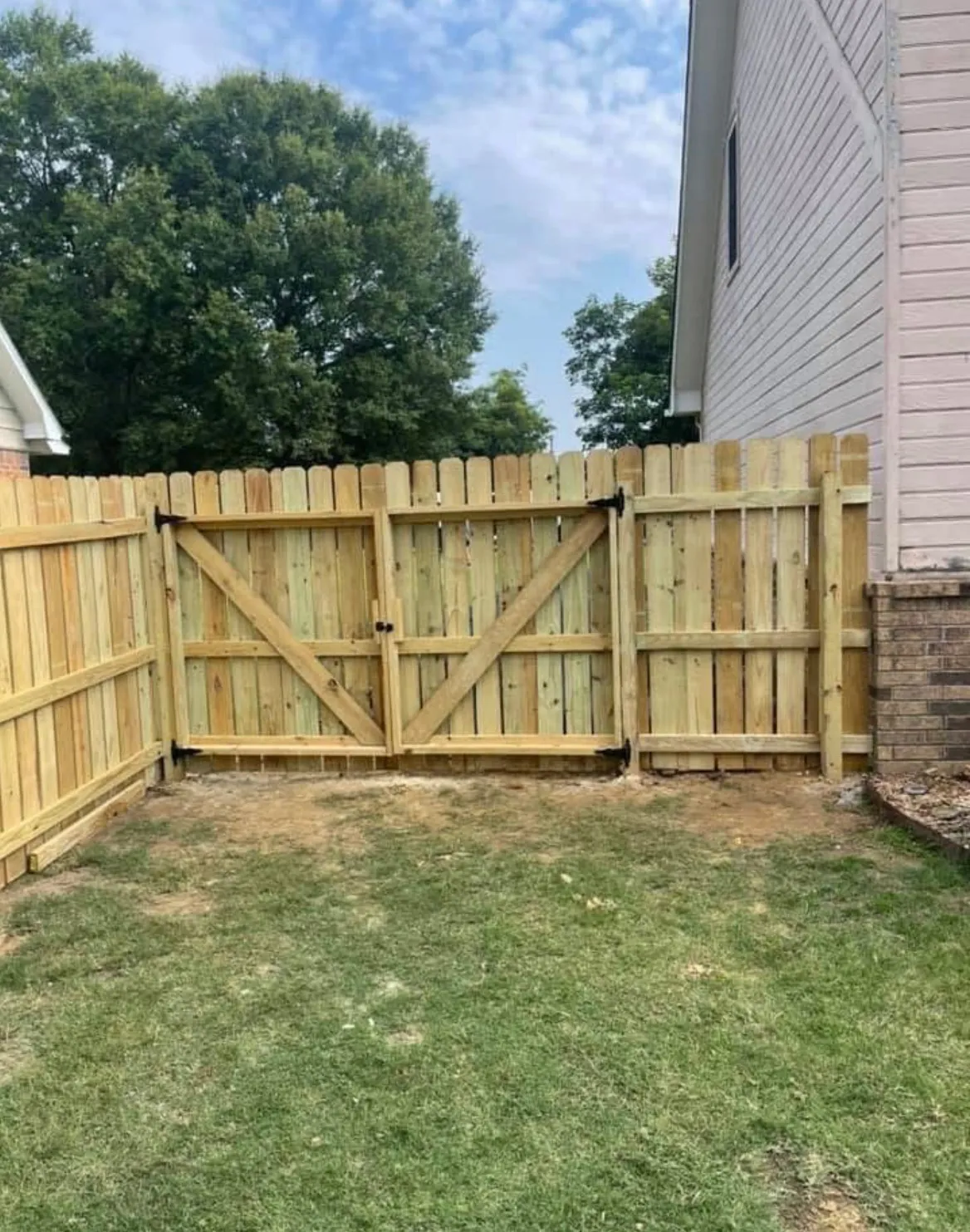 New wood privacy fence with a matching double gate and diagonal bracing enclosing a backyard in Springdale, AR