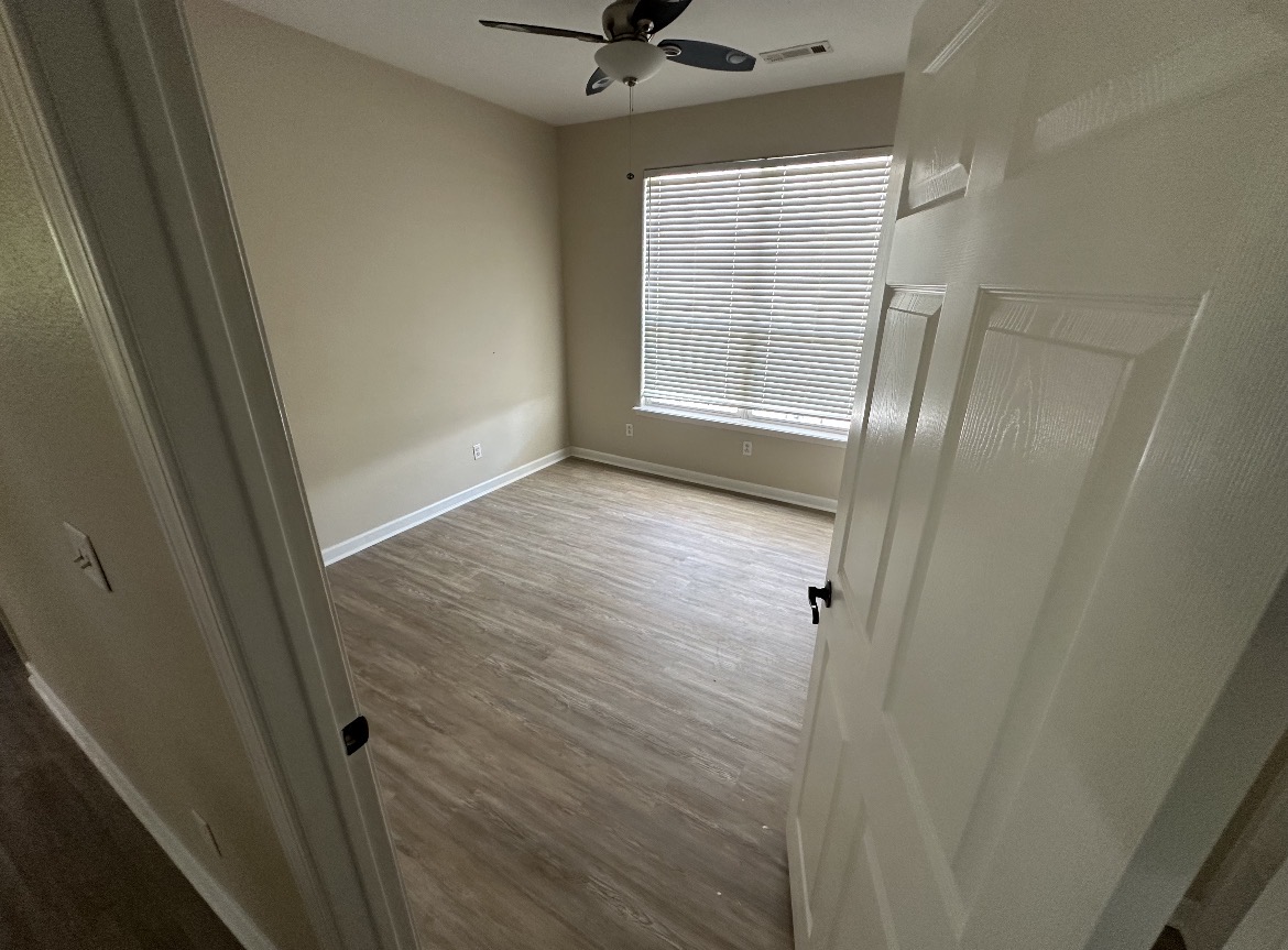 Bedroom with new gray wood-look plank flooring, fresh baseboards, and a bright window