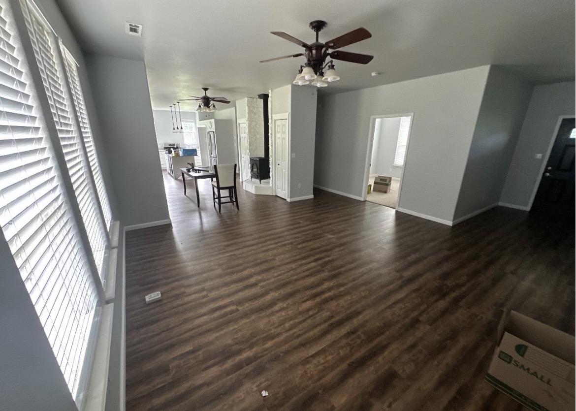 Spacious living and dining area with dark wood-look plank flooring and an open view to the kitchen