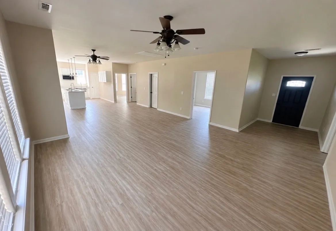 Open-concept living area with new light wood-look luxury vinyl plank flooring flowing into the kitchen