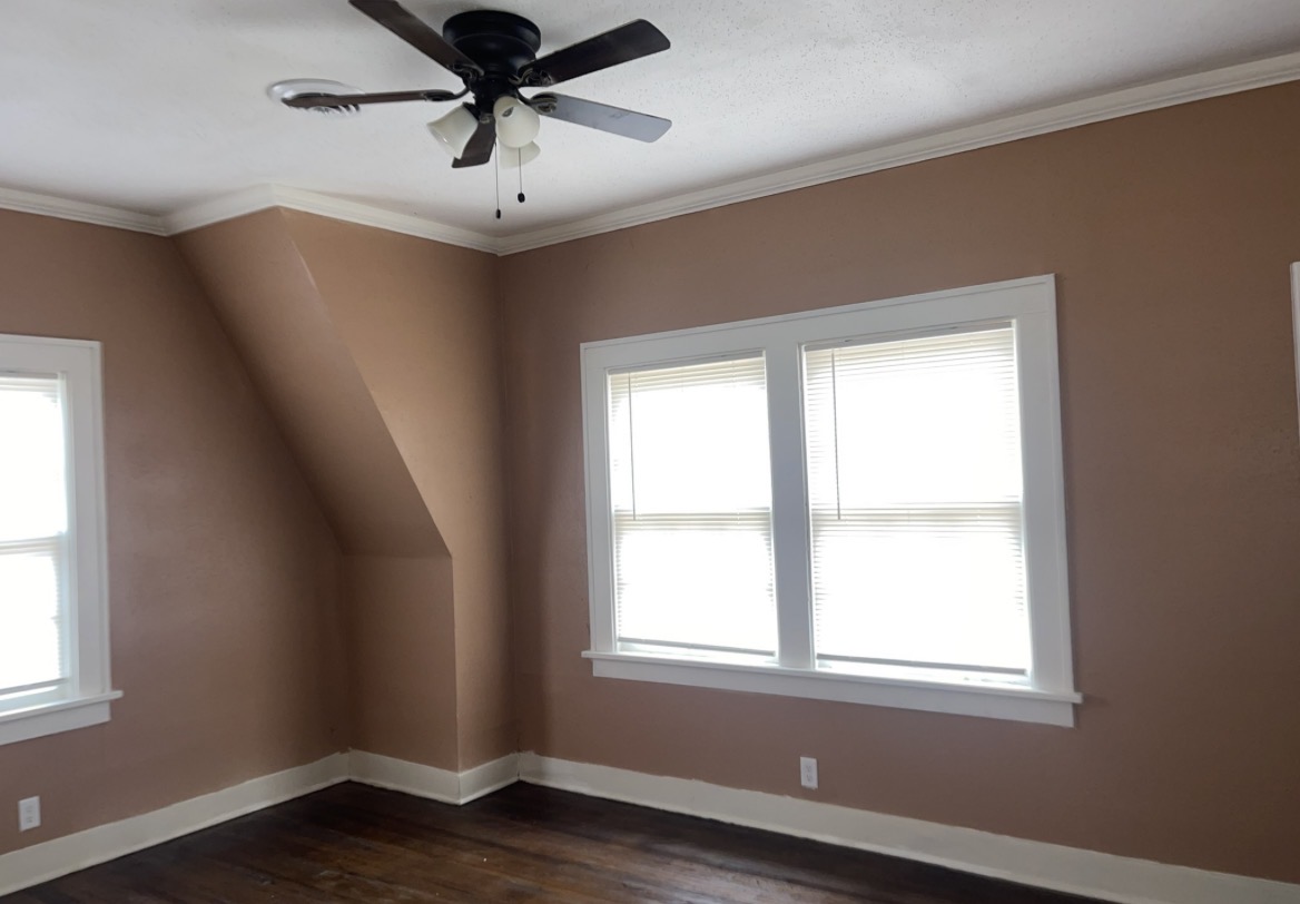 Bedroom being repainted, with a ladder, protective floor covering, and freshly coated warm-tone walls