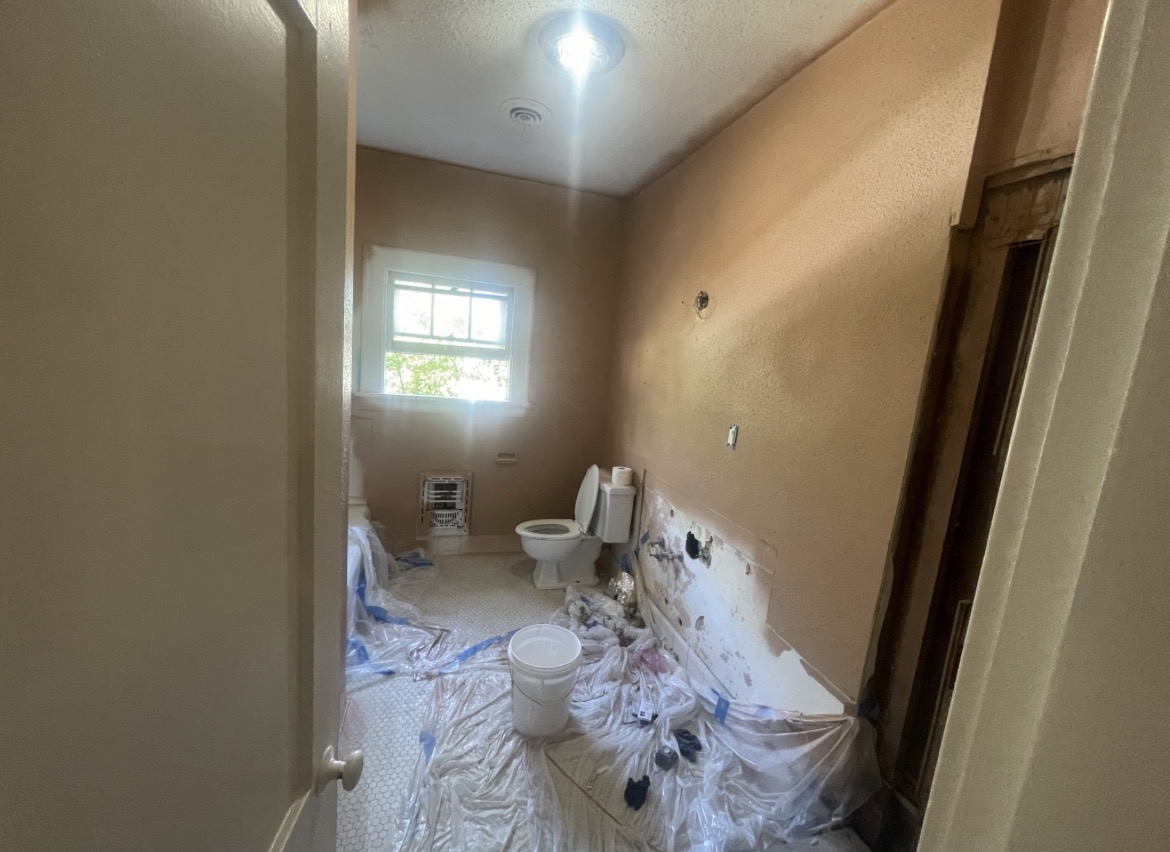 Freshly painted bedroom with warm mocha walls, crisp white trim and crown molding, refinished dark hardwood floors, and a ceiling fan
