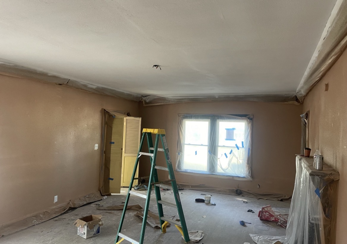 Newly painted bedroom with mocha walls, bright white window trim, and refinished dark wood flooring