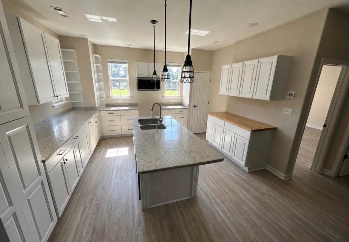 U-shaped kitchen remodel with white cabinets, speckled granite countertops, open shelving, and a large island